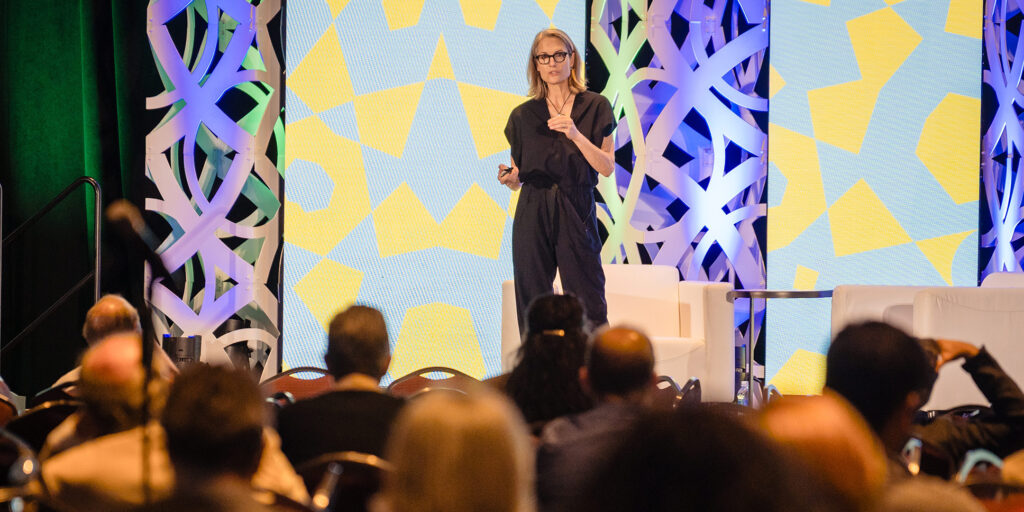 Conference speaker presenting in front of a large audience.