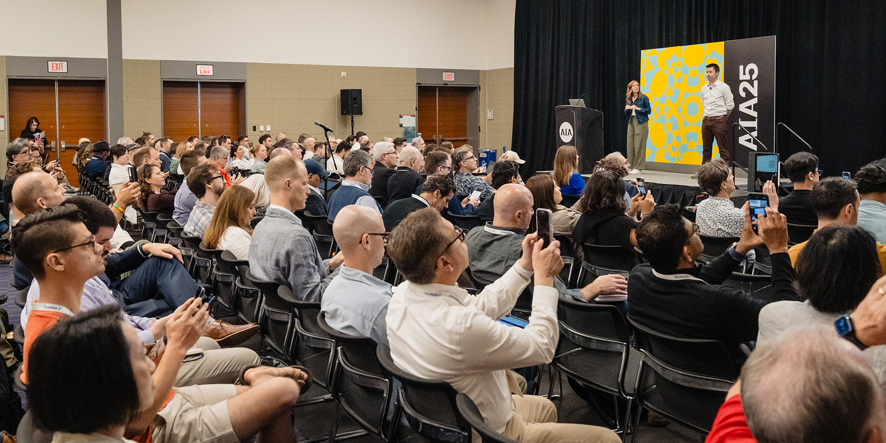 Audience of architects taking photos of the education session they are participating in.