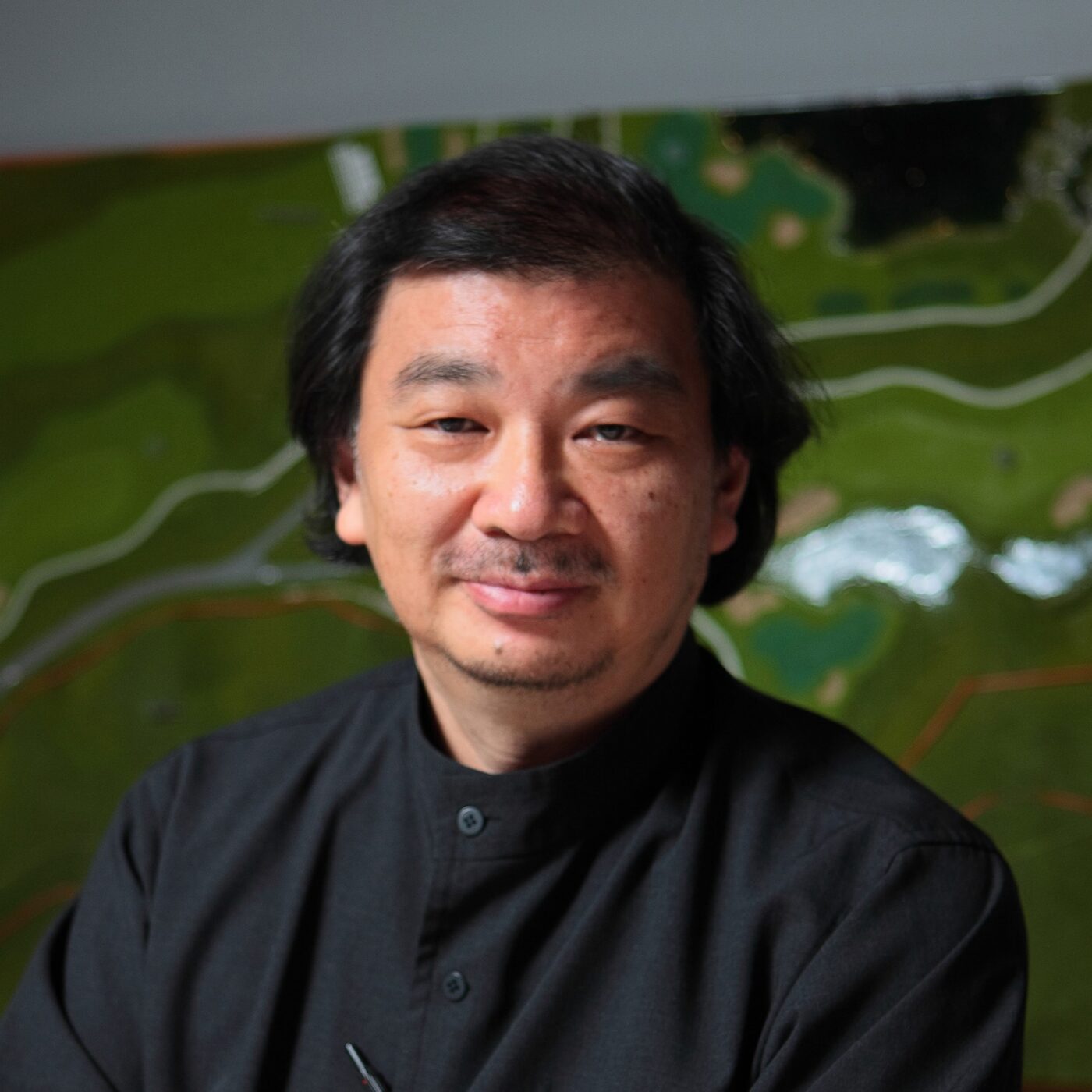 Headshot of Shigeru Ban who revolutionized architecture with renewable materials like paper and timber, creating resilient, sustainable designs like disaster shelters and the Cardboard Cathedral.
