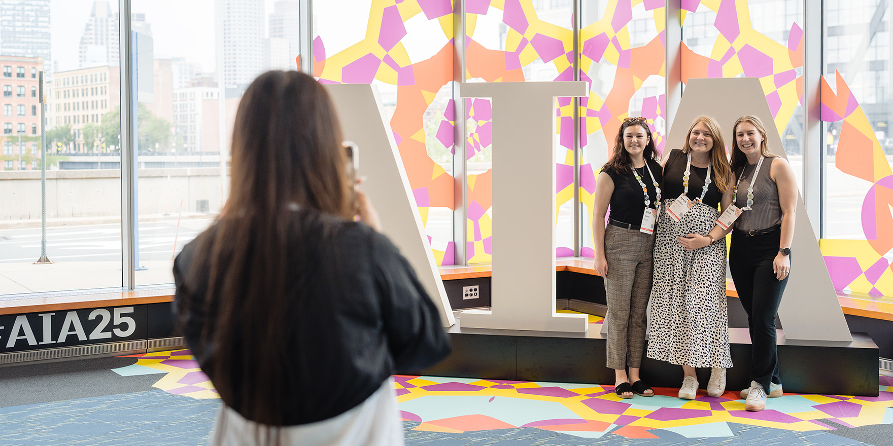 Group of women having fun and taking pictures in front of large AIA letters at the Conference on Architecture & Design.